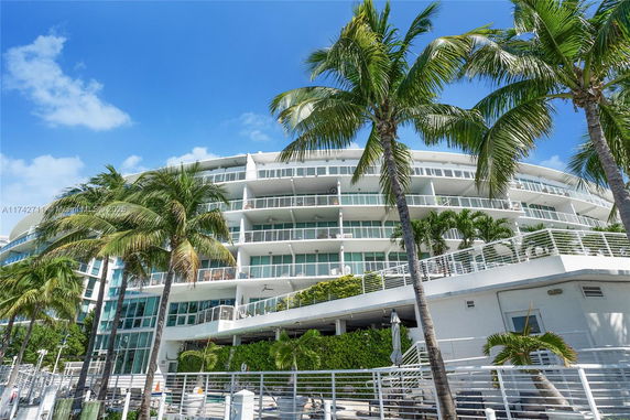 Front view of a multi-story building with balconies and palm trees.