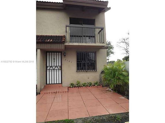 Front view of a two-story house with a balcony and tiled entryway.