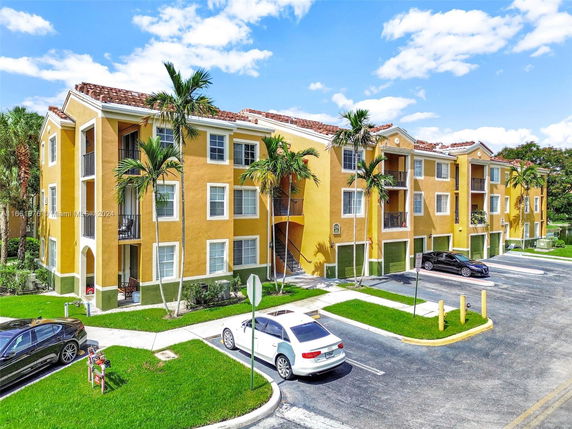 Front view of a multi-story residential building with multiple balconies and parking area.