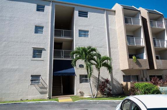 Front view of a multi-story residential building with balconies and a staircase entrance.