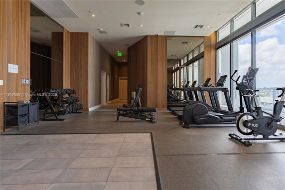 Interior view of a gym with treadmills and exercise equipment next to large windows.