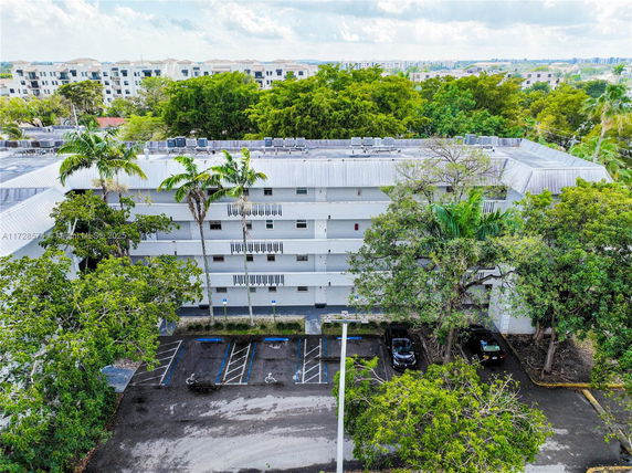 Front view of a multi-story building with a flat roof and parking area.