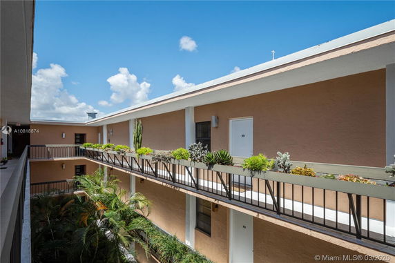 View of a multi-level building with balconies adorned with plants and railings.