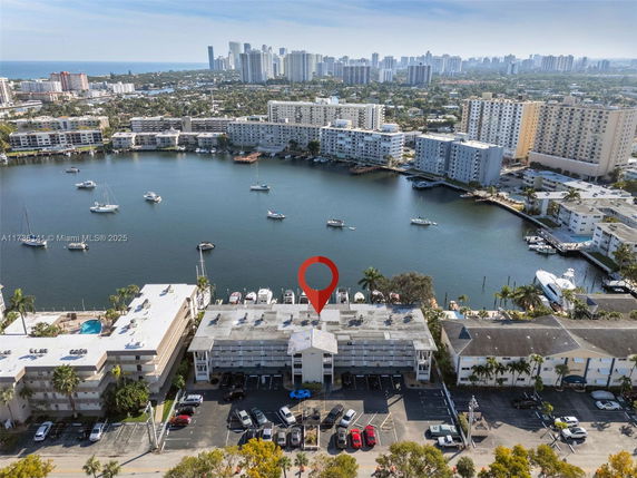 Aerial view of a waterfront area with several mid-rise buildings and boats docked along the water.
