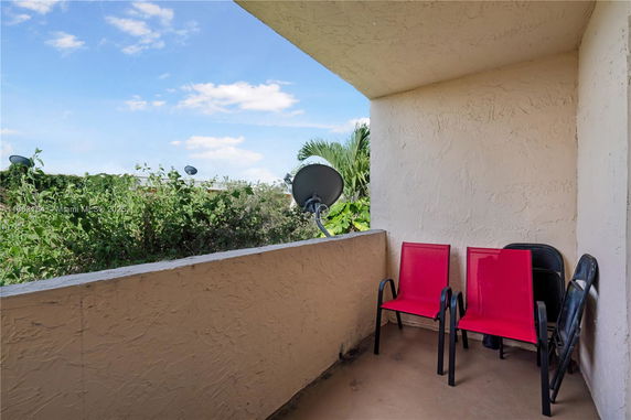 Balcony view with chairs and satellite dish overlooking greenery.