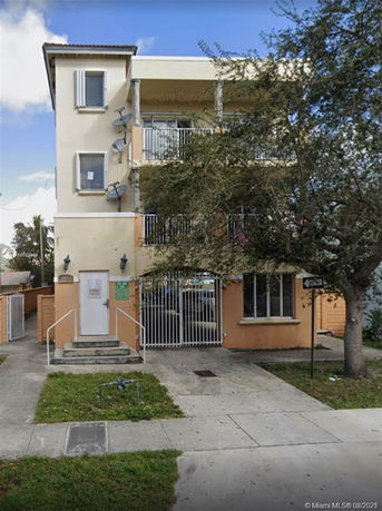Front view of a three-story building with balconies and multiple satellite dishes.