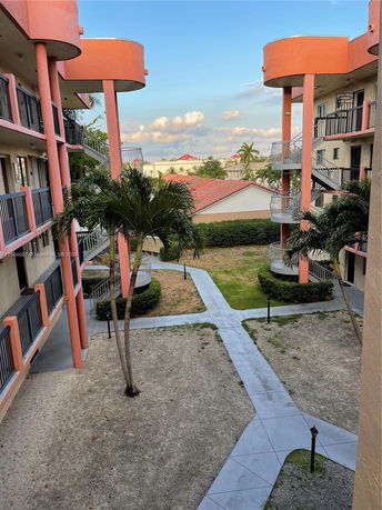 View of a multi-story building with balconies and pathways in the surrounding courtyard.