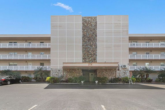 Front view of a multi-story building with balconies and decorative stone facade.
