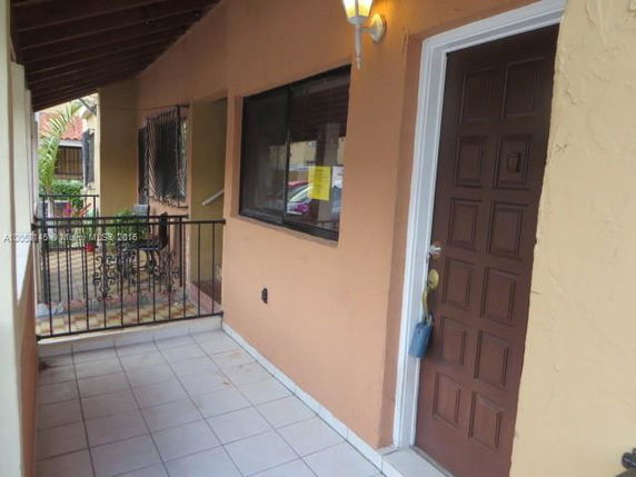 Front view of a house entrance with a brown door and tiled walkway.