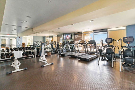 Indoor gym with exercise equipment including treadmills and weights.