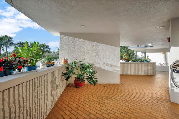 Covered outdoor area with potted plants on a tiled floor.