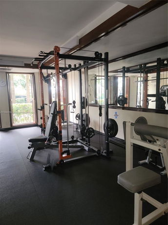 Indoor gym area with weightlifting equipment and mirrors.