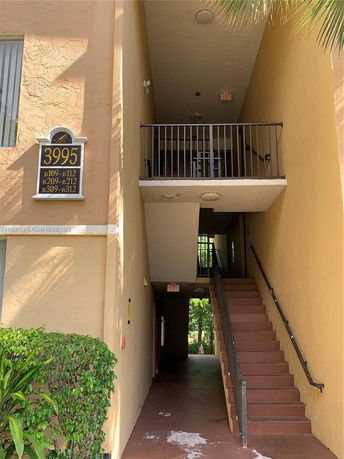 Front view of a multi-story building with an exterior staircase and a visible apartment number sign.