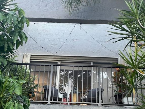 Front view of a balcony with patio furniture and string lights.
