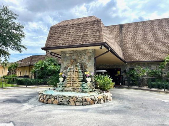 Front view of a building with a stone facade and a decorative stone fountain in the entrance area.