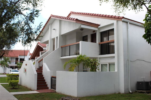 Front view of a multi-story building with balconies and an external staircase.