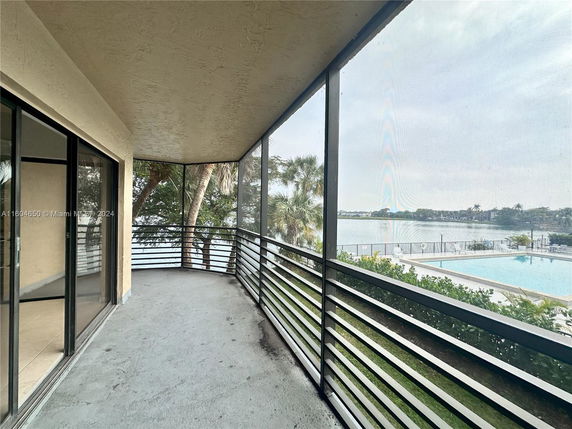 View from a screened balcony overlooking a pool and water body.