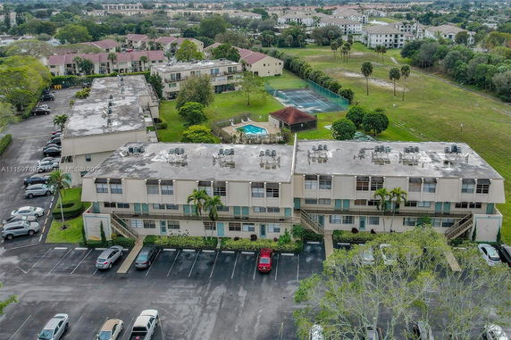 Aerial view of residential buildings with parking lot and tennis court.