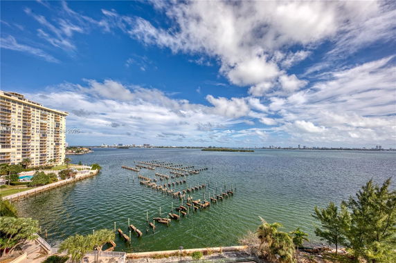 Panoramic view of a waterfront area with a high-rise building on the left and water extending into the distance with docks.