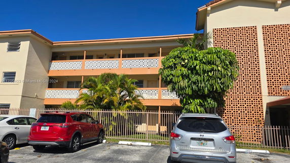 Front view of a multi-story residential building with balconies and a patterned facade.