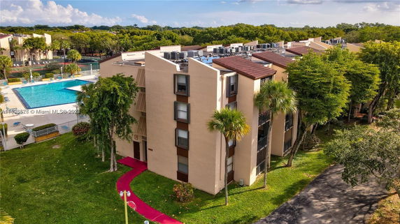 Aerial view of residential buildings with a swimming pool and green surroundings.