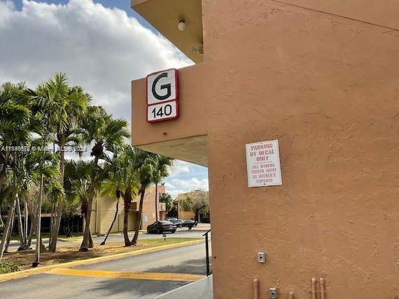 Outdoor parking area adjacent to a building corner with signage.
