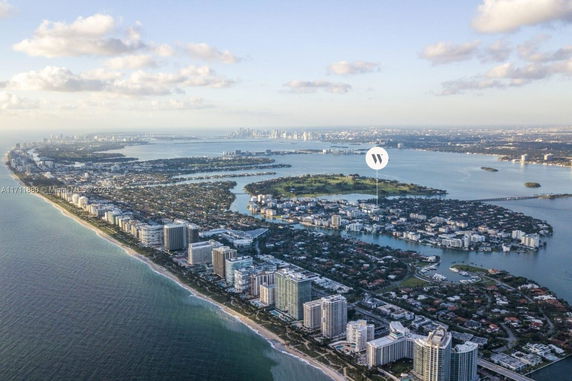 Aerial panoramic view of coastal buildings and landscape with ocean and cityscape in the distance.