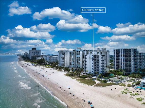 Aerial view of beachfront high-rise buildings along a sandy beach.