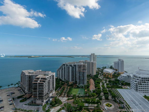 Wide view of tall buildings near a body of water, with a bridge in the background.