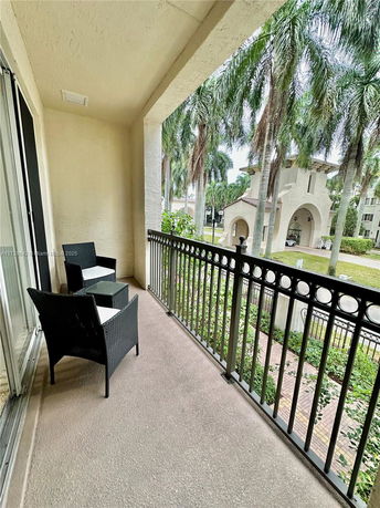 View from a balcony showing neighboring buildings and palm trees.