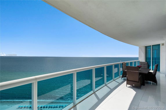 Outdoor balcony with seating overlooking the ocean.