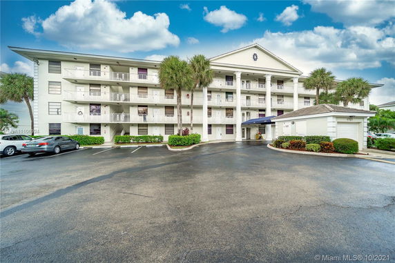Front view of a multi-story residential building with balconies and a covered entrance.