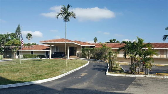 Front view of a single-story building with a tile roof and surrounding driveway.