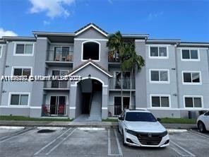 Front view of a three-story residential building with parking in front.