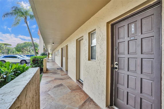 Outdoor corridor with building entrance and visible parking area.