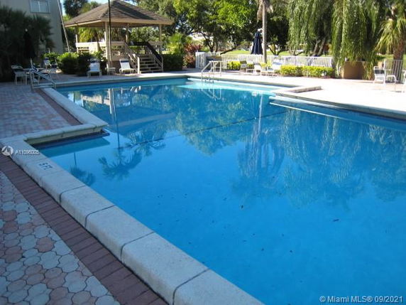 Outdoor swimming pool with surrounding greenery and seating area.