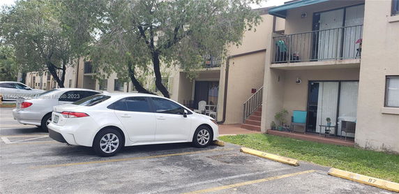 Outdoor parking area with cars in front of an apartment building.