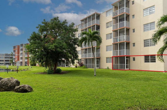 View of a multi-story building with balconies and surrounding green lawn.