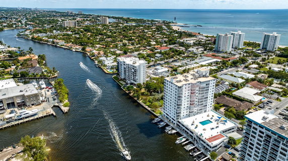 Aerial view of a coastal cityscape with waterways, buildings, and distant ocean.