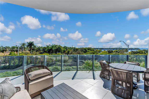 Terrace with seating area overlooking lush greenery and a distant view of the water.
