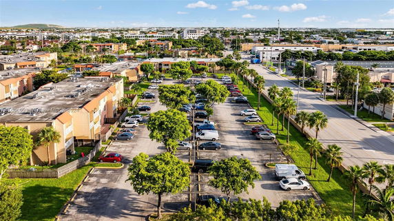 Outdoor parking area with multiple cars and nearby buildings.