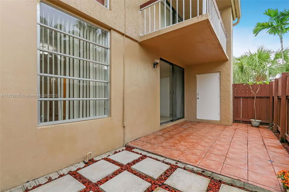 Exterior view of a building with a small tiled patio and large window.