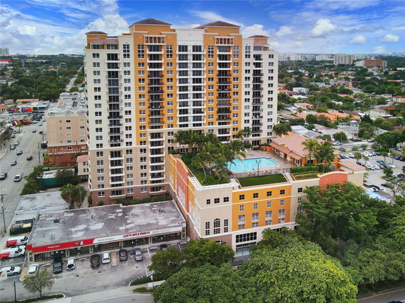 Front view of a large multi-story residential building with balconies and a pool area.