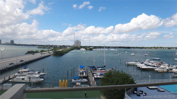 Scenic view of a marina with boats docked in a waterway and a bridge in the background.