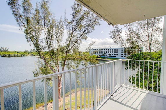 View from a balcony overlooking a lake and distant buildings.
