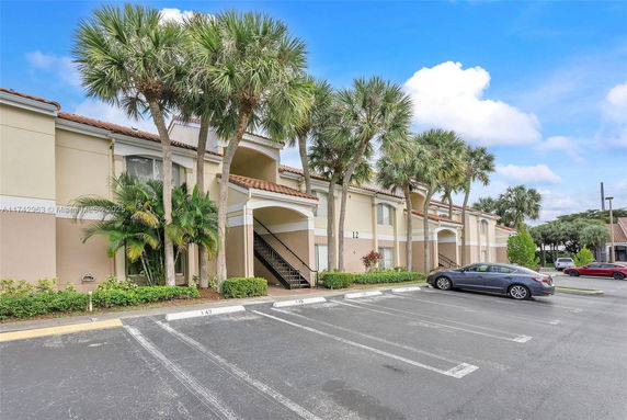 Front view of a two-story building with arched entrances and palm trees.