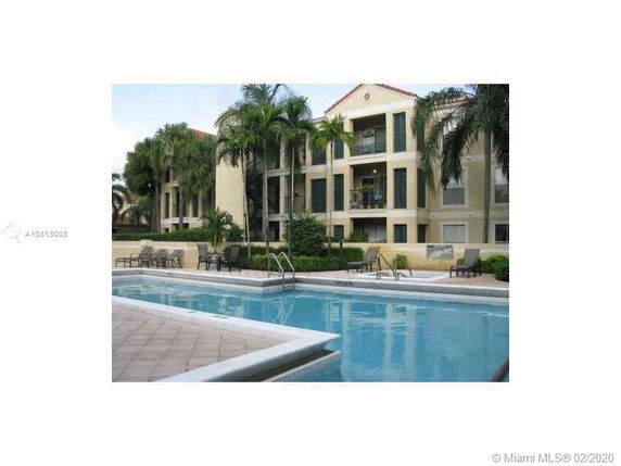 View of an apartment complex with a pool in the foreground.