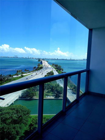 Panoramic view from a balcony overlooking a highway and body of water.
