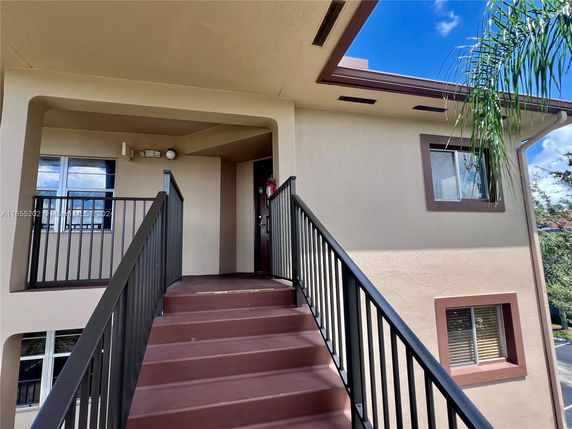 Entrance to a two-story residential building with an exterior staircase.