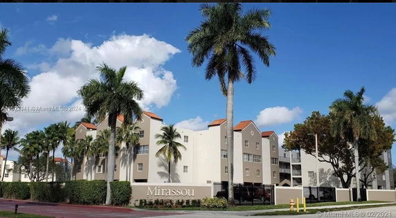 Front view of a multi-story residential condominium building with palm trees.